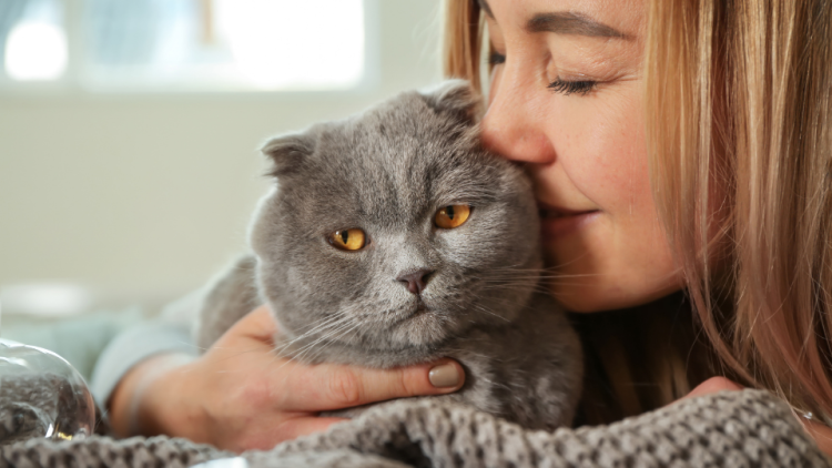 woman kissing cat's cheek